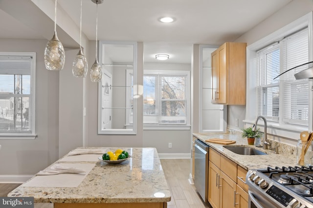 kitchen featuring stainless steel appliances, hanging light fixtures, light brown cabinets, a sink, and light stone countertops