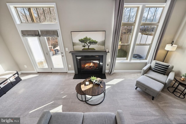 sitting room with a fireplace with flush hearth, carpet flooring, and baseboards