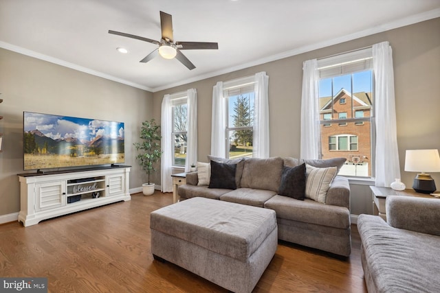 living area with a ceiling fan, crown molding, baseboards, and wood finished floors