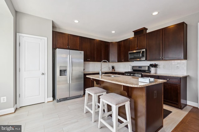 kitchen featuring a breakfast bar area, appliances with stainless steel finishes, backsplash, and a sink