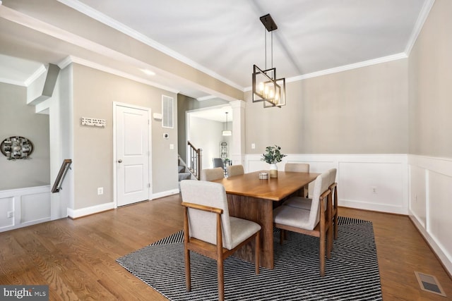 dining room featuring a wainscoted wall, wood finished floors, visible vents, and crown molding