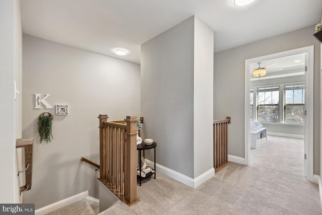 hall with carpet, an upstairs landing, and baseboards