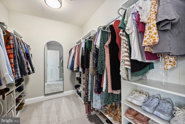 spacious closet featuring arched walkways and carpet flooring