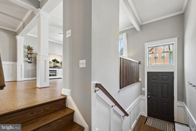 foyer featuring a decorative wall, wainscoting, decorative columns, and crown molding