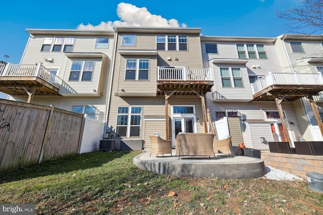 rear view of property featuring a lawn, a balcony, a fenced backyard, a patio area, and central AC