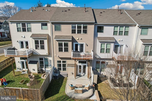 rear view of property featuring a residential view, roof with shingles, a lawn, and cooling unit