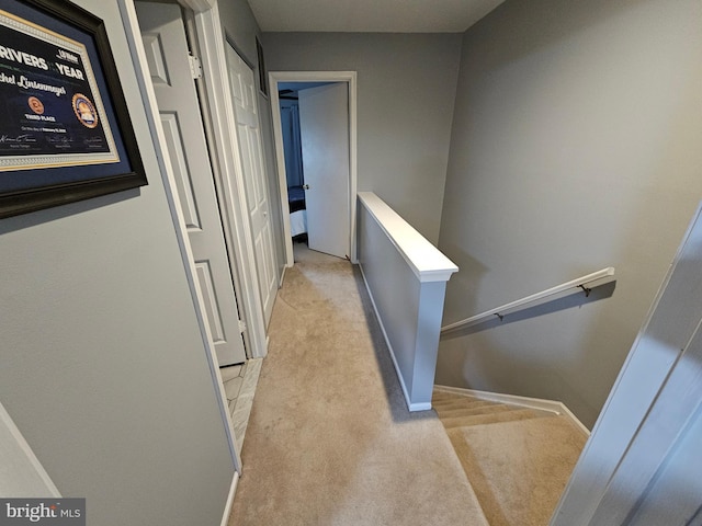 hall with baseboards, light colored carpet, and an upstairs landing