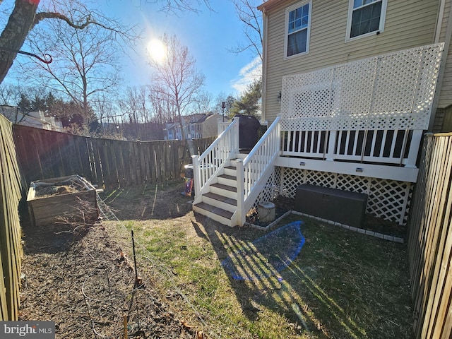 view of yard with stairway, a fenced backyard, and a wooden deck