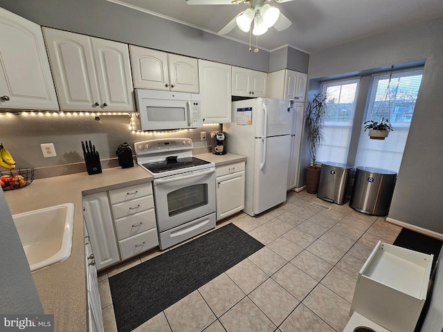 kitchen featuring white appliances, light countertops, a sink, and white cabinetry