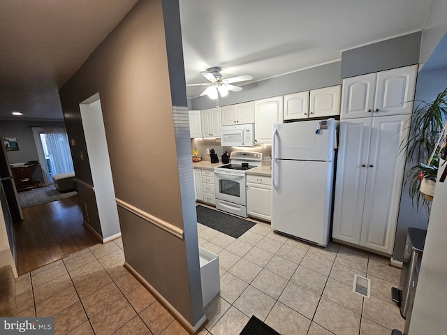 kitchen featuring light tile patterned flooring, white appliances, visible vents, white cabinets, and light countertops