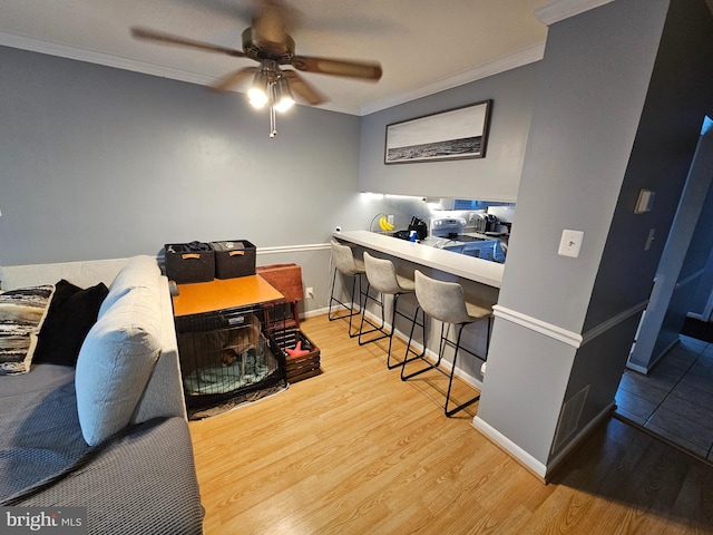 office space with light wood-style floors, crown molding, baseboards, and a ceiling fan