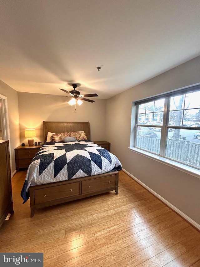 bedroom featuring light wood-style flooring, baseboards, and a ceiling fan