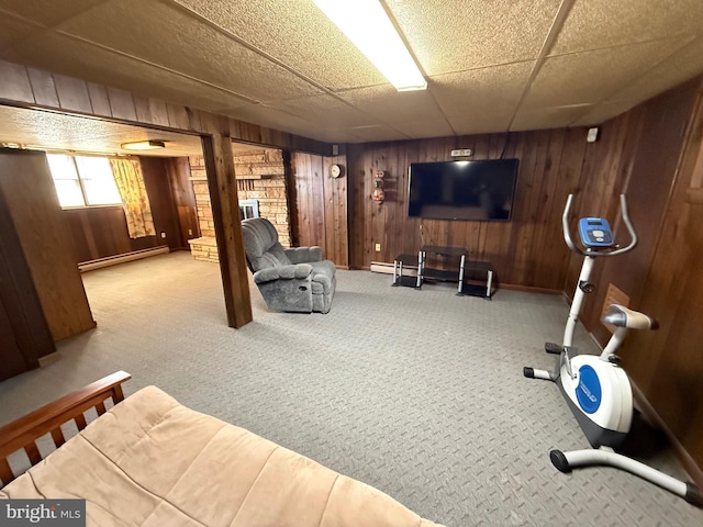 workout area featuring a baseboard heating unit, a paneled ceiling, carpet floors, and wooden walls