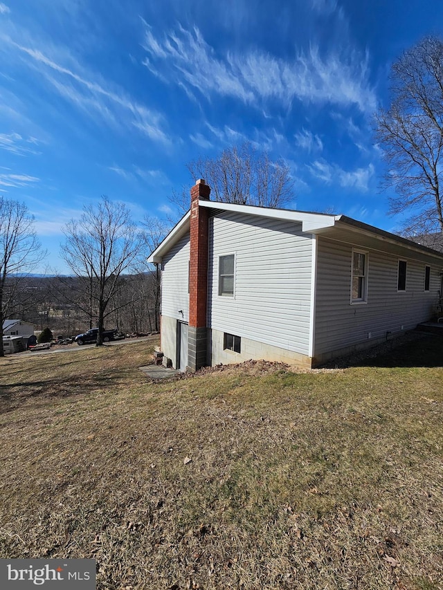 view of home's exterior with a chimney and a yard