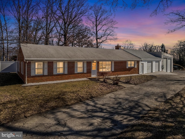 ranch-style home featuring brick siding, a chimney, concrete driveway, an attached garage, and fence