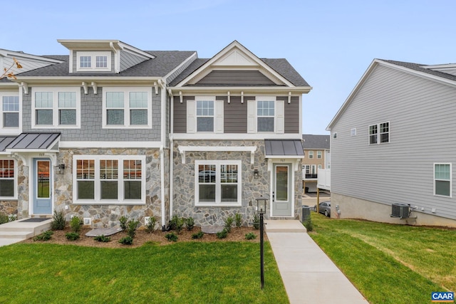 view of front facade featuring a front yard, a standing seam roof, and central AC