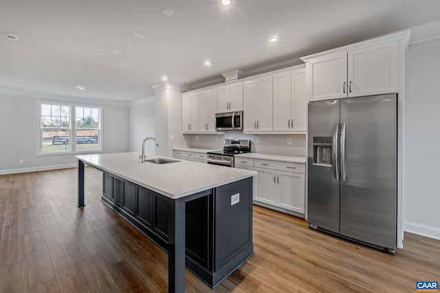 kitchen with stainless steel appliances, a sink, white cabinets, light countertops, and an island with sink