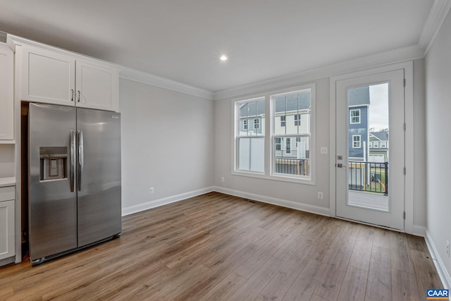 kitchen with stainless steel fridge with ice dispenser, ornamental molding, white cabinetry, light wood-type flooring, and baseboards