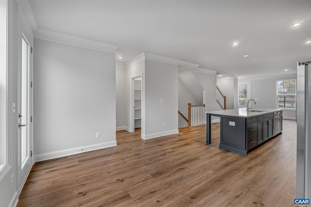 kitchen featuring a breakfast bar, light countertops, a sink, an island with sink, and wood finished floors