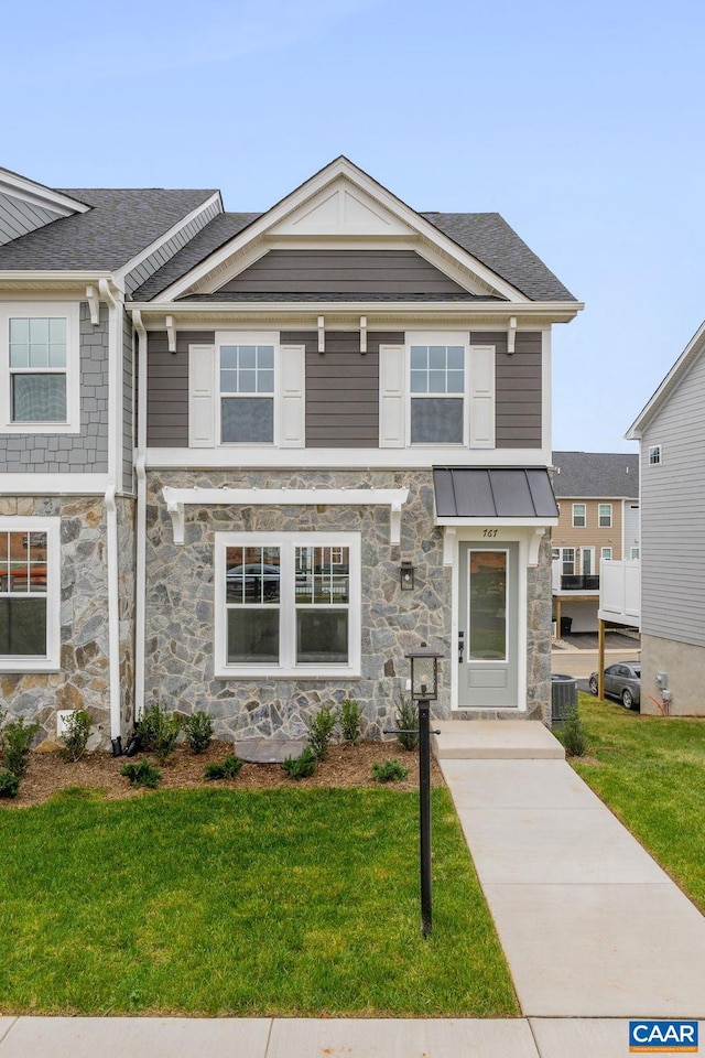 view of front of property featuring stone siding, a front lawn, and a standing seam roof