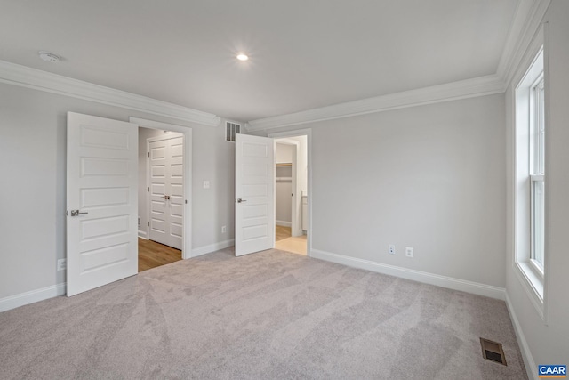 unfurnished bedroom featuring ornamental molding, light colored carpet, visible vents, and baseboards