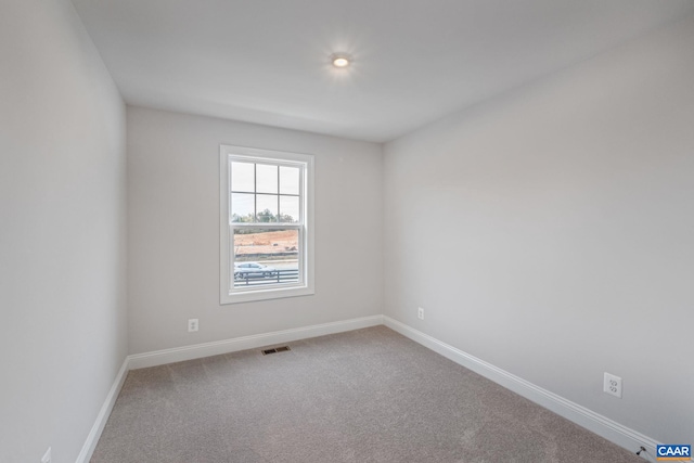 empty room with carpet flooring, visible vents, and baseboards