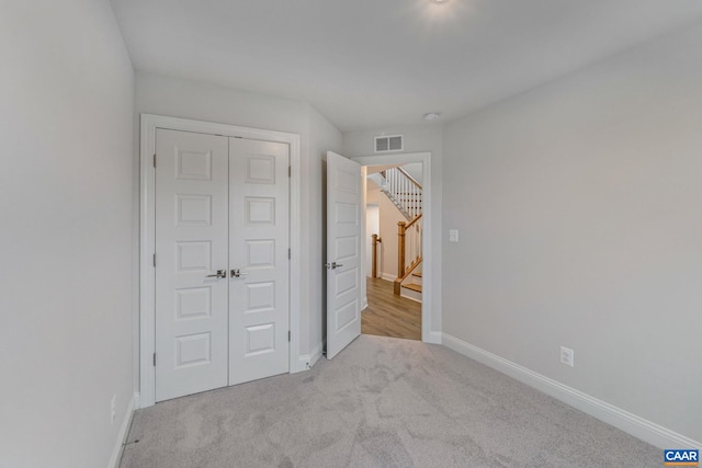 unfurnished bedroom with light carpet, a closet, visible vents, and baseboards