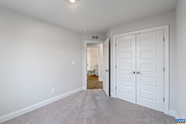 unfurnished bedroom featuring a closet, baseboards, visible vents, and carpet flooring