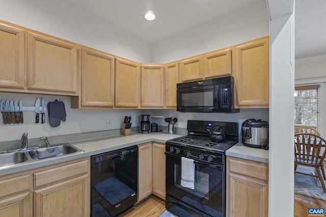 kitchen featuring light countertops, a sink, black appliances, and light brown cabinetry