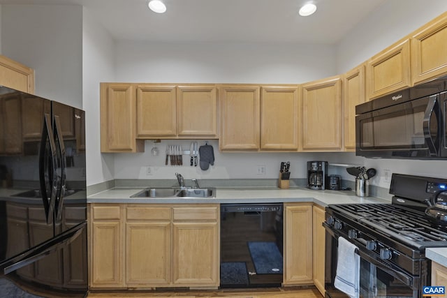 kitchen featuring light countertops, a sink, black appliances, and light brown cabinetry