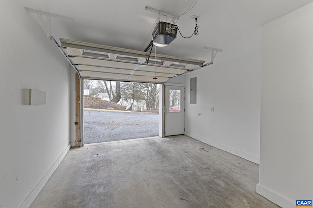 garage featuring a garage door opener, electric panel, and baseboards