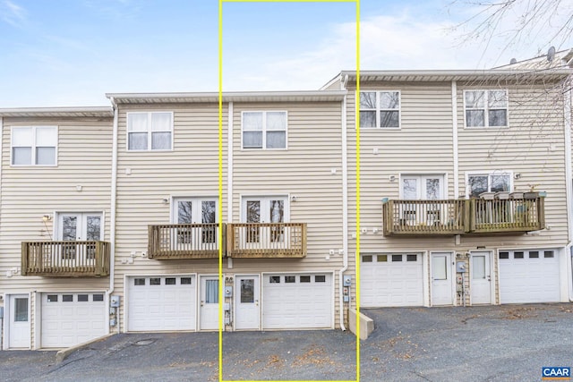 rear view of house with a garage, driveway, and a balcony