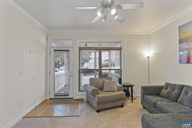 living area featuring baseboards, light carpet, a ceiling fan, and crown molding