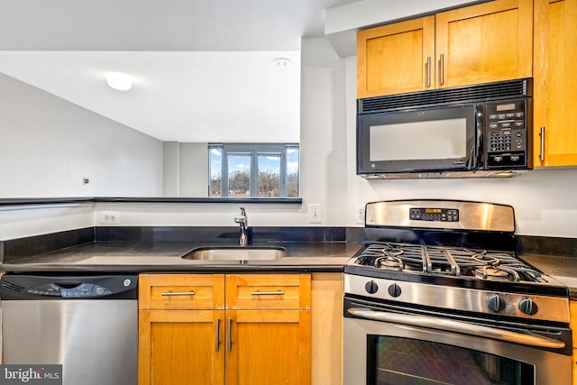 kitchen featuring dark countertops, appliances with stainless steel finishes, brown cabinets, and a sink