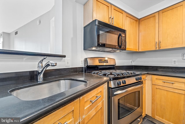 kitchen featuring black microwave, a sink, stainless steel gas range, brown cabinetry, and dark stone countertops