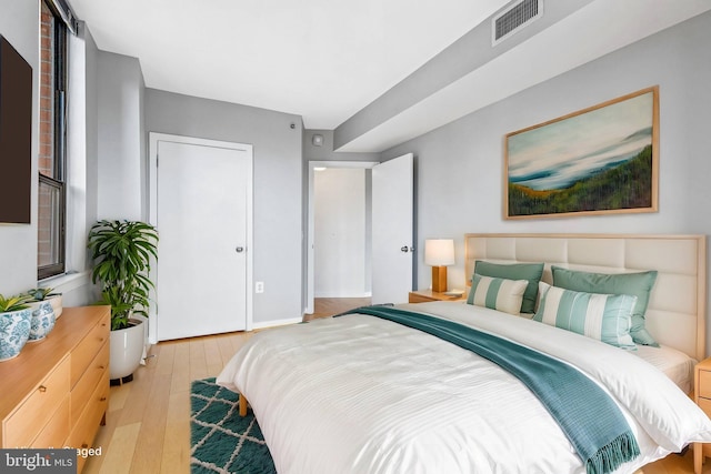 bedroom featuring visible vents, baseboards, and wood finished floors