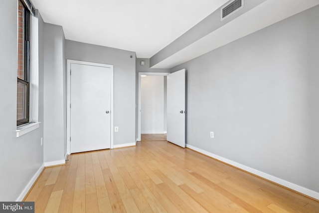 unfurnished bedroom featuring visible vents, baseboards, and hardwood / wood-style flooring