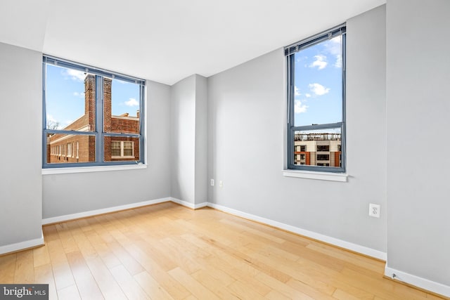 spare room with baseboards and wood finished floors