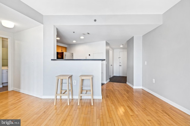 kitchen with dark countertops, light wood finished floors, baseboards, and freestanding refrigerator