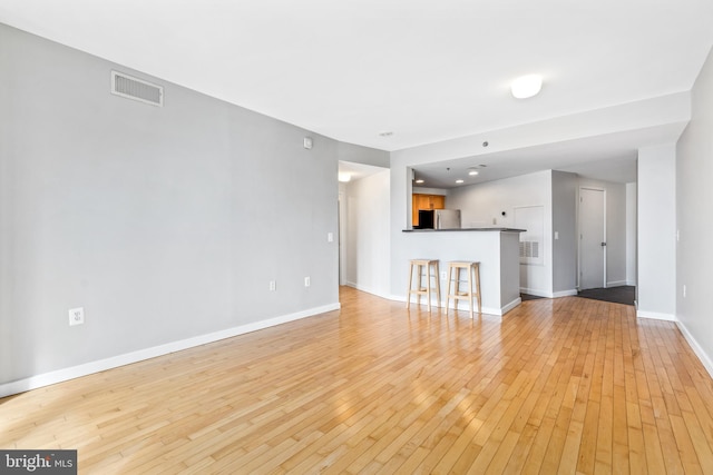 unfurnished living room featuring light wood-type flooring, baseboards, and visible vents