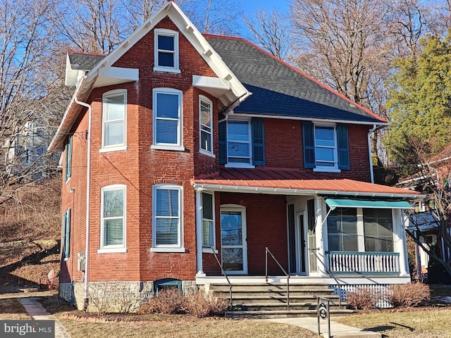 view of front of house with a porch, a standing seam roof, brick siding, and metal roof