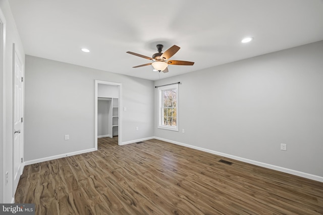 unfurnished bedroom featuring baseboards, visible vents, wood finished floors, a walk in closet, and recessed lighting