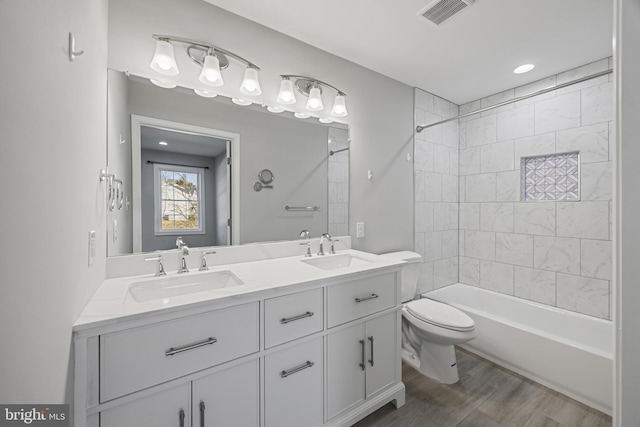 bathroom featuring visible vents, a sink, toilet, and double vanity