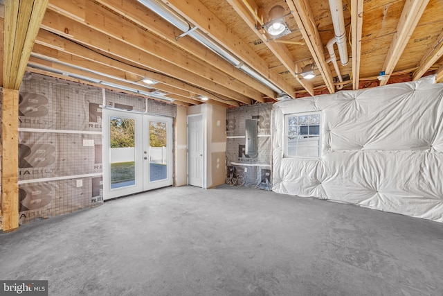 basement with french doors, electric panel, and a healthy amount of sunlight