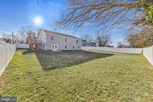 rear view of house featuring a lawn and a fenced backyard