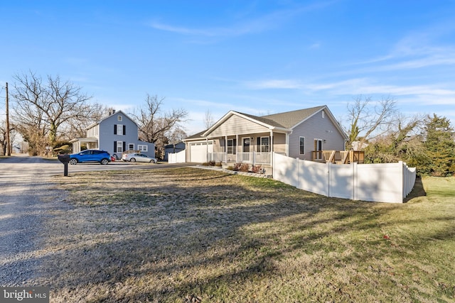 view of front facade with driveway, a garage, a porch, fence, and a front lawn