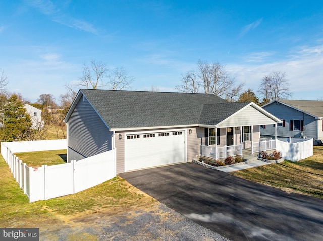 view of front of house with covered porch, an attached garage, a front yard, fence, and driveway