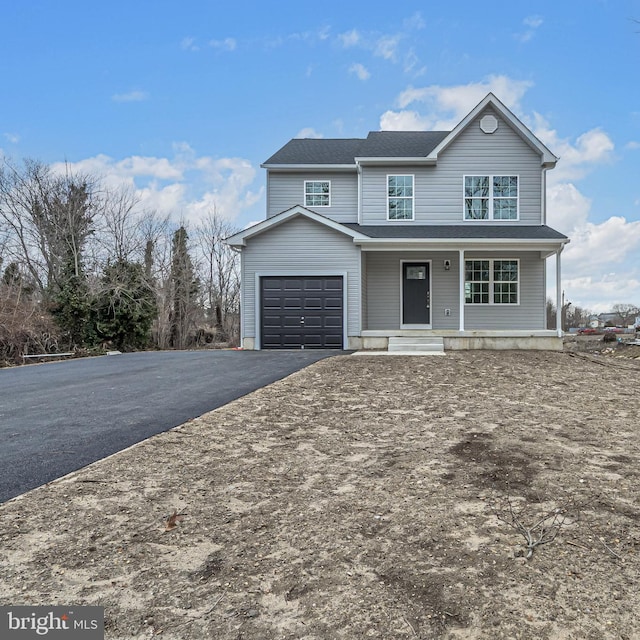 traditional home with covered porch, aphalt driveway, and a garage