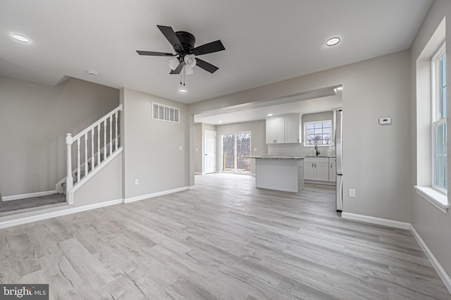 unfurnished living room with light wood-style flooring, recessed lighting, visible vents, baseboards, and stairs