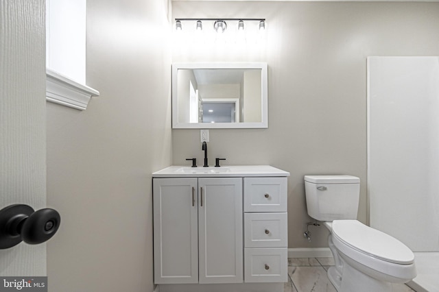 bathroom with marble finish floor, vanity, toilet, and baseboards